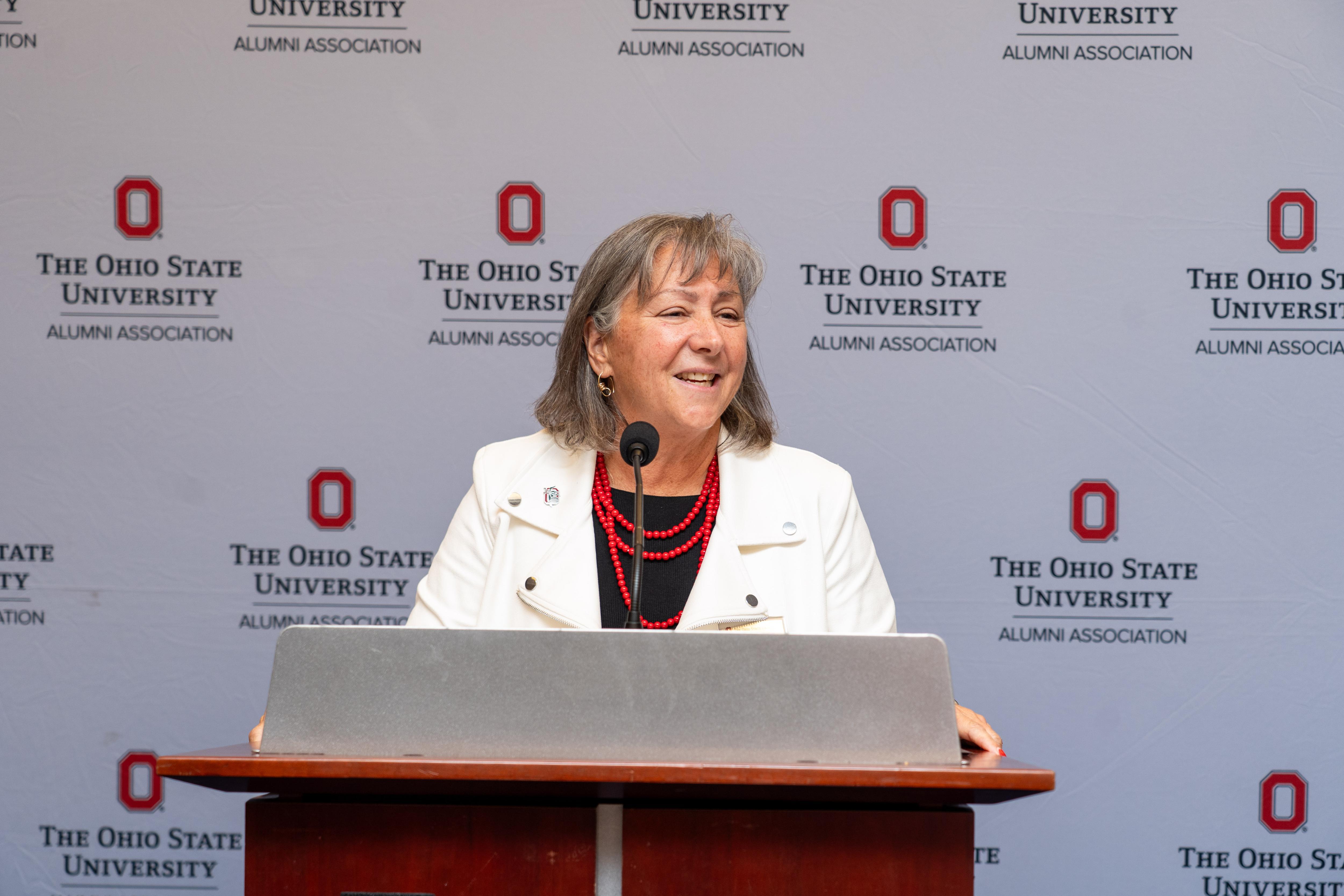 Ohio State University Alumni Association President Molly Ranz Calhoun stands at a podium.